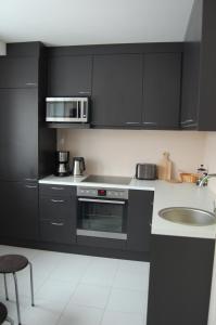塔林Kaunis Guesthouse的厨房配有黑色橱柜、水槽和微波炉
