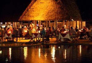 蒙巴萨蒙巴萨里弗酒店的一群人晚上坐在水边的桌子上