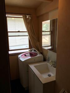 小笠原香提简易别墅的小型浴室设有洗衣机和水槽。