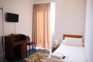 塔拉戈纳皮加尔酒店的一间卧室配有一张床、一张书桌和一台电视