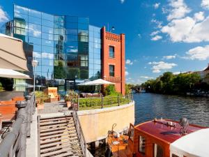 柏林ABION别墅套房式酒店的停靠在河边一座建筑物旁边的船只