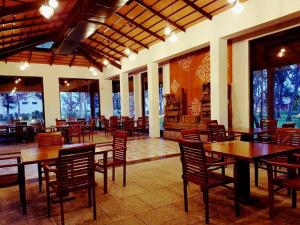 钦奈VGP黄金海岸度假酒店的餐厅设有木桌、椅子和窗户。