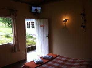 康塞桑-杜马图登特鲁Pousada Tabuleiro Eco的一间卧室配有一张床,另一扇门配有电视