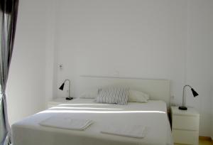 马克里亚罗斯Helios Studios & Apartments的一张白色的床,上面有两盏灯