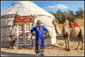 TaldyAidar Yurt Camp的站在圆顶帐篷前骆驼旁的人