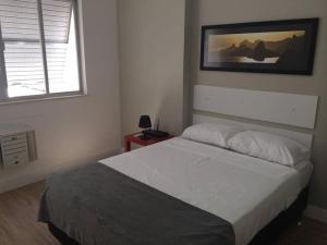 里约热内卢apartamento luxo copacabana的卧室配有一张床,墙上挂着一幅画