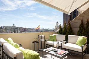 马德里马德里帕维里昂酒店的阳台配有沙发,享有城市美景