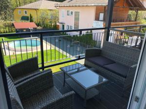 沃尔特湖畔韦尔登得其乐旅馆的一个带两把椅子和一张桌子的阳台以及一个游泳池