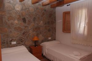 巴尔巴特芬卡埃尔阿布埃罗酒店的一间卧室设有两张床和石墙