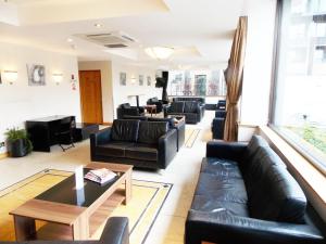 伦敦伦敦 - 温布利国际酒店的客厅配有黑色真皮沙发和桌子