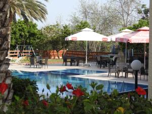 帕福斯安娜酒店公寓的一个带桌椅和遮阳伞的游泳池