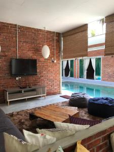 Huma丹绒鲁泳池TRV度假屋的一间带砖墙和游泳池的客厅
