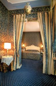 威尼斯洛坎达卡德布罗基酒店的一间卧室配有一张天蓬床和一张带台灯的桌子