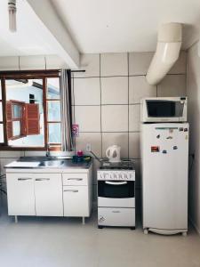 弗洛里亚诺波利斯Lagoa da Conceição Apartments的小厨房配有炉灶和冰箱
