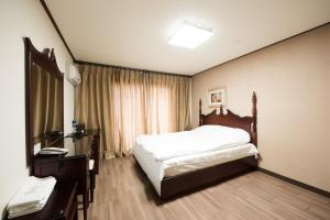 郁陵迪乌隆度假村的一间卧室配有一张床、一张书桌和一个窗户。