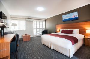 CabramattaRamada Hotel & Suites by Wyndham Cabramatta的酒店客房设有一张大床和一张书桌。