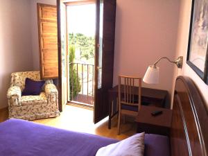 塞哥维亚拉朱德里亚住宿酒店的一间卧室配有一张床、一张书桌和一个窗户。