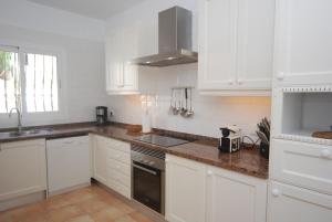 卡拉隆加Villa Sa Seni的厨房配有白色橱柜和炉灶烤箱。