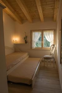 加尔达Alle Vignole的一间卧室设有两张床、一把椅子和一个窗户。