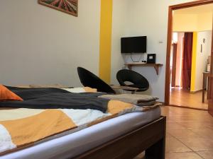 久洛AIDA Apartman的一间卧室配有一张带两把椅子的床和电视。
