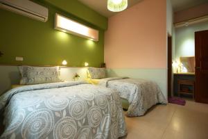 吉安呼吸民宿的卧室设有两张床铺和绿色的墙壁