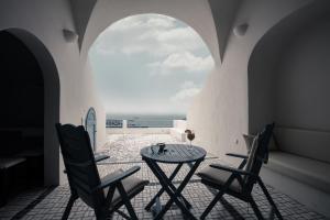 易莫洛林La Maltese Private House Imerovigli的一间设有两把椅子、一张桌子和一个窗户的房间
