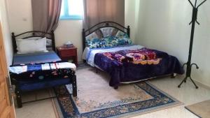 泰夫劳特Azur Tafraout的一间卧室配有两张床、一张桌子和一张床套。