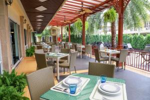 芭堤雅市中心芭提雅黄金海酒店 - SHA Extra Plus的庭院内的餐厅,配有桌椅