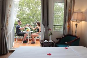 河内Hanoi Siva Luxury Hotel & Travel的坐在酒店房间桌子上的男女