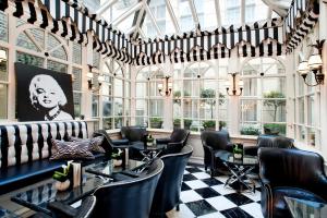 伦敦红色康乃馨肯辛顿里程碑酒店的餐厅设有黑椅子和桌子以及窗户。