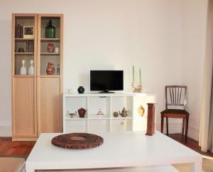 里斯本Casa da Varanda Simpática的一间客厅,在白色的橱柜上配有电视