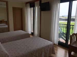 Ribadumia圣塔拜亚旅馆的一间卧室设有两张床和大窗户