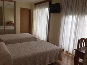 Ribadumia圣塔拜亚旅馆的一间卧室设有两张床、一张桌子和一个窗口