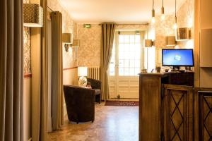 萨尔特河畔勒梅勒Logis Hôtel Restaurant de la Poste的一间带电视、椅子和窗户的客厅