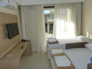 皮拉伊河畔巴拉Aldeia das Águas Park Resort - Flat Quartier的一间卧室设有两张床、一台电视和一扇窗户。