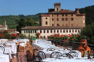 巴罗洛Hotel Barolo Classico的一间设有白色桌椅的餐厅,以及一座城堡