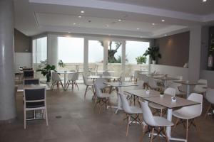 内尔哈太阳门广场酒店的餐厅设有桌子和白色的椅子以及窗户。