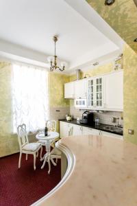 圣彼得堡Symfonia的厨房配有白色橱柜和桌椅