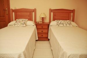 奥亚Casa Toñi的一间卧室配有两张床和一个带灯的梳妆台。