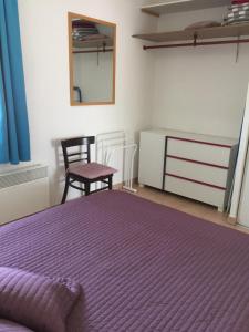 格吕桑Appartement dans Les jardins de Phoebus的一间卧室配有一张紫色的床和一把椅子