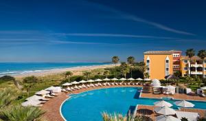 奇克拉纳－德拉弗龙特拉Palacio de Sancti Petri, a Gran Meliá Hotel的一个带遮阳伞的游泳池和海滩的度假胜地