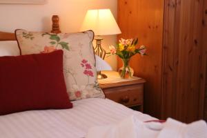 赫尔斯顿Mandeley Guest House的一张带枕头的床和一张桌子上的花瓶