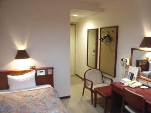 郡山郡山微笑酒店的酒店客房带一张床、一张书桌和一面镜子