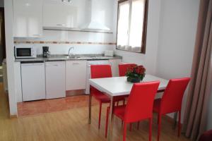 仕格莱Apartamentos San Lázaro的厨房配有白色的桌子和红色的椅子