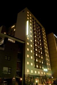 金泽Dormy Inn Kanazawa Natural Hot Spring的一座高大的建筑,晚上有灯
