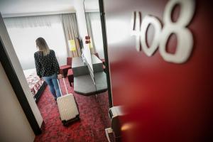林茨ARCOTEL Nike Linz的一位妇女带着手提箱站在酒店房间