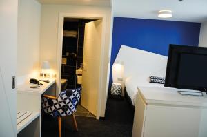 斯特拉斯堡折纸酒店的一间卧室配有一张床和一张书桌及电视