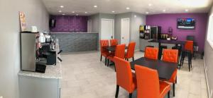 索诺拉Super 8 by Wyndham Sonora的餐厅设有橙色椅子、桌子和紫色墙壁