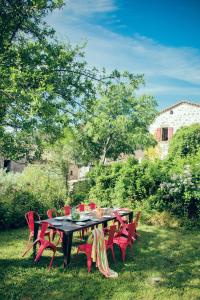 SanilhacLe Domaine du Fayet的院子里一张带红色椅子的黑桌子