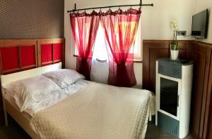 波波林Marlin - pokoje nad morzem的一间卧室配有一张带红色窗帘的床和一扇窗户